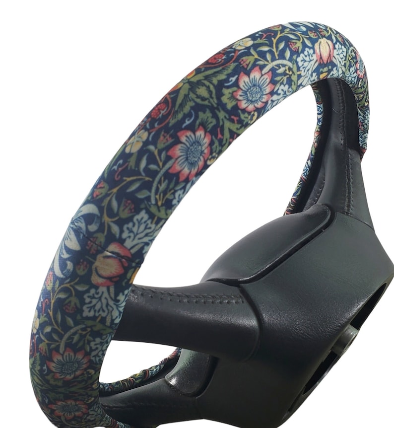 Pu&ograve; includere: Una copertura per volante con un motivo floreale nei toni del blu, rosso e verde. La copertura &egrave; avvolta attorno a un volante nero. Il design floreale presenta fiori e foglie dettagliate.