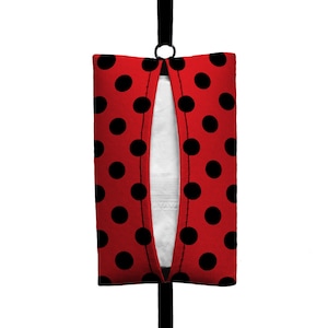 May include: Red tissue box cover with black polka dots. The cover has a flap that opens to reveal a tissue box.
