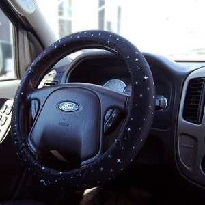 May include: A black steering wheel with a blue and white star pattern cover. The steering wheel has a silver Ford logo and the word "Escape" written below it.