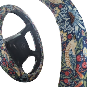 Pu&ograve; includere: Coprivolante con un motivo floreale e di uccelli colorato. La copertura presenta uno sfondo blu scuro con accenti bianchi, rossi, gialli e verdi. Il volante &egrave; nero.
