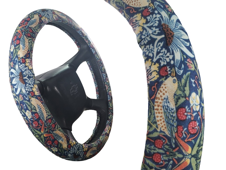 Pu&ograve; includere: Coprivolante con un motivo floreale e di uccelli colorato. La copertura presenta uno sfondo blu scuro con accenti bianchi, rossi, gialli e verdi. Il volante &egrave; nero.