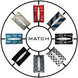 Puede incluir: Un estante circular de metal negro con ocho porta pañuelos. Los porta pañuelos están decorados con diferentes patrones, incluyendo anclas, elefantes, lunares y diseños geométricos. La palabra "MATCH" está impresa en el centro del estante.