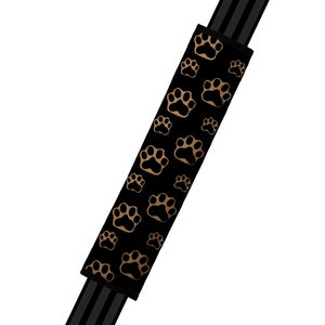 Könnte beinhalten: Schwarzer Autositzgurtbezug mit goldfarbenem Pfotenabdruckmuster.