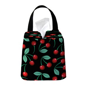 May include: Black tissue box cover with a cherry print. The cover has a black handle and a white tissue box inside.