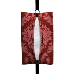May include: A red tissue holder with a pink floral pattern. The holder has a black strap and a zipper opening.