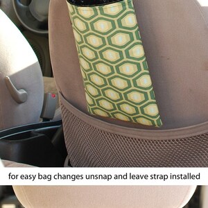 May include: A green and yellow patterned car trash bag holder with a black strap that attaches to the headrest of a car seat. The strap has a snap closure for easy bag changes. The text "for easy bag changes unsnap and leave strap installed" is visible below the image.