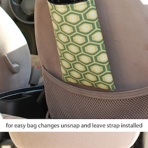 May include: A green and yellow patterned car trash bag holder with a black strap that hangs from the headrest of a car seat. The strap has a snap closure for easy bag changes. "For easy bag changes unsnap and leave strap installed" is written below the image.