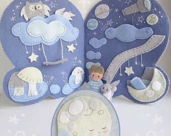 May include: A felt book for children with a blue background and various felt appliques, including a moon, stars, clouds, a mushroom, an owl, a telescope, and a boy. The book is open to reveal the inside pages.