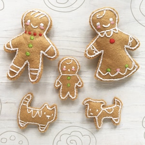 May include: A set of five felt gingerbread ornaments, including two gingerbread people, a gingerbread child, a cat, and a dog. The ornaments are decorated with white stitching and colorful embroidery.