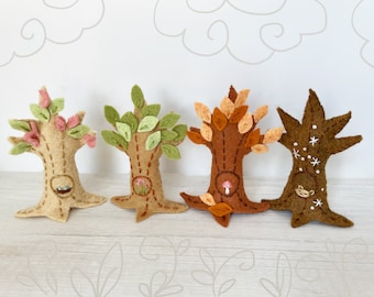 May include: Four felt trees in different seasons: spring with pink flowers, summer with green leaves, autumn with orange leaves, and winter with white snowflakes. Each tree has a brown trunk and a stitched bird's nest.