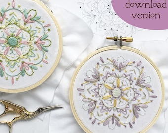 May include: Two embroidery hoops with floral designs. The hoop on the left has a green, pink, and yellow design. The hoop on the right has a purple, yellow, and green design. The hoops are on a white fabric background.  PDF download version.
