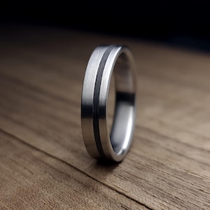 以下が含まれることがあります： 黒いインレイが付いた銀の指輪。指輪はブラッシュ仕上げで、ポリッシュ仕上げになっています。