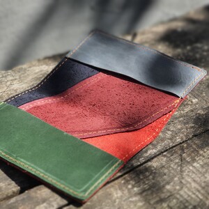 Könnte beinhalten: Eine mehrfarbige Ledergeldbörse mit einem grünen, roten, orangen und blauen Design. Die Geldbörse hat einen genähten Rand und ist in der Mitte gefaltet.