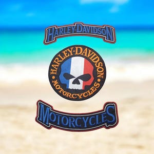 Peut inclure: Trois patchs brodés Harley-Davidson. Le patch du haut est une bannière bleue et rouge avec le texte "Harley-Davidson". Le patch du milieu est un cercle noir avec un crâne et des os croisés blancs, un drapeau français et le texte "Harley-Davidson Motorcycles". Le patch du bas est une bannière bleue et rouge avec le texte "Motorcycles".