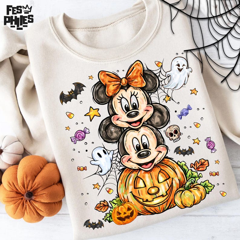 Puede incluir: Sudadera crema con un dise&ntilde;o de Halloween. El dise&ntilde;o incluye a Mickey y Minnie Mouse, una calabaza tallada, fantasmas, murci&eacute;lagos, caramelos y una telara&ntilde;a. Los personajes est&aacute;n apilados sobre una calabaza.