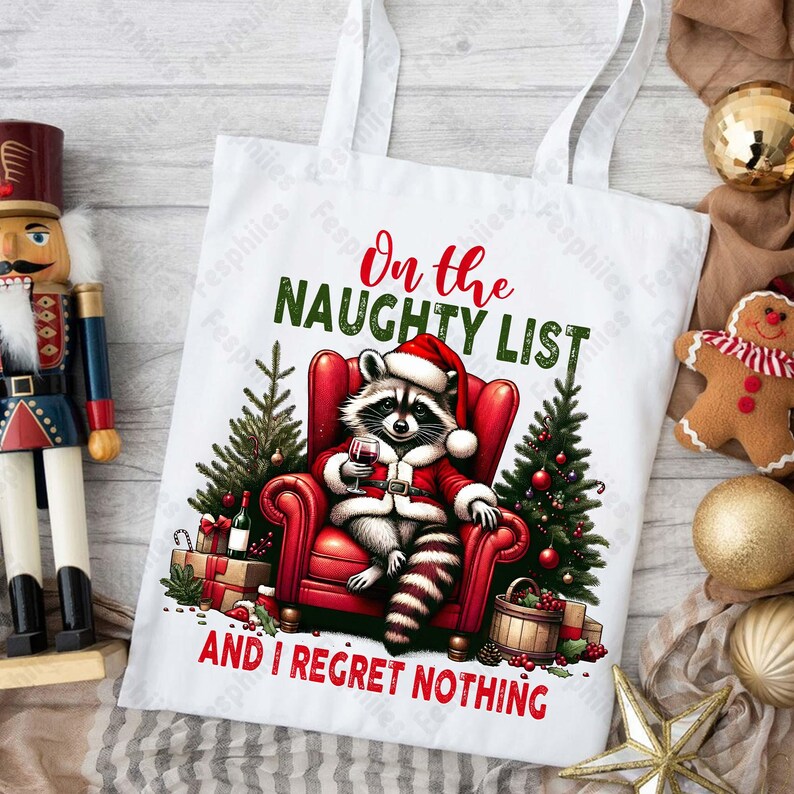 May include: White tote bag with a red and black raccoon wearing a Santa hat and holding a glass of wine. The text on the bag reads "On the Naughty List and I Regret Nothing."