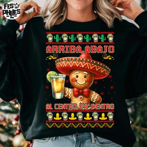 May include: Black sweatshirt with a gingerbread man wearing a sombrero and holding a shot of tequila with a lime wedge. The text "ARRIBA, ABAJO, AL CENTRO, PA' DENTRO" is printed on the shirt.
