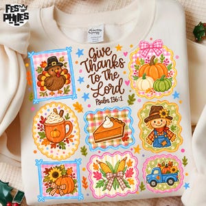 Puede incluir: Una sudadera color crema con un gráfico central que dice "Give Thanks to the Lord Psalm 136:1" rodeado de ilustraciones de un pavo, calabaza, bebida caliente, trozo de tarta, espantapájaros, maíz y un camión azul en marcos coloridos.