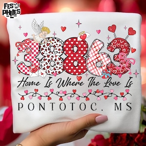 May include: White t-shirt with the numbers "3863" in red and white patterns, with the text "Home Is Where The Love Is" and "PONTOTOC, MS". The design includes hearts, an angel, and decorative elements.
