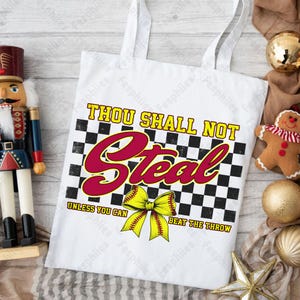 May include: White tote bag with a black and white checkered background. The text "Thou Shall Not Steal Unless You Can Beat The Throw" is printed in red and black. A yellow softball with a bow is in the center of the bag.