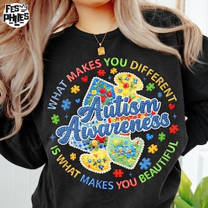 May include: Black sweatshirt with the text "What Makes You Different Is What Makes You Beautiful" surrounding a puzzle piece design. The design includes the words "Autism Awareness" and colorful floral patterns.