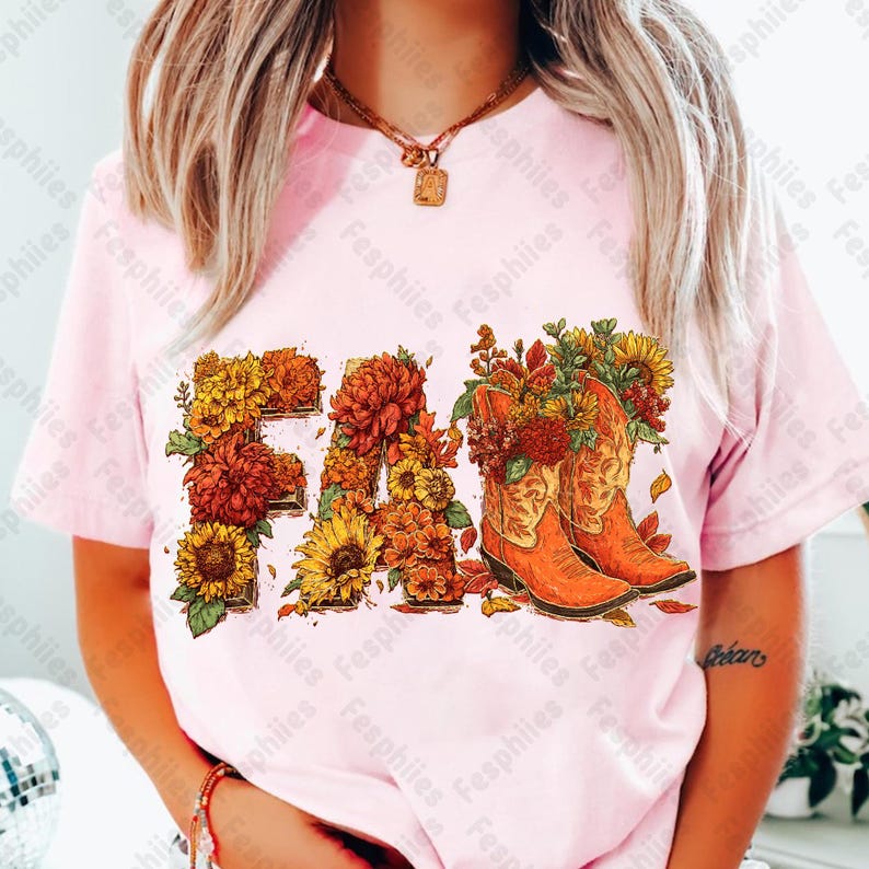 May include: Pale pink t-shirt featuring the word "FALL" in a floral design, with orange cowboy boots. The floral arrangement includes sunflowers and chrysanthemums.