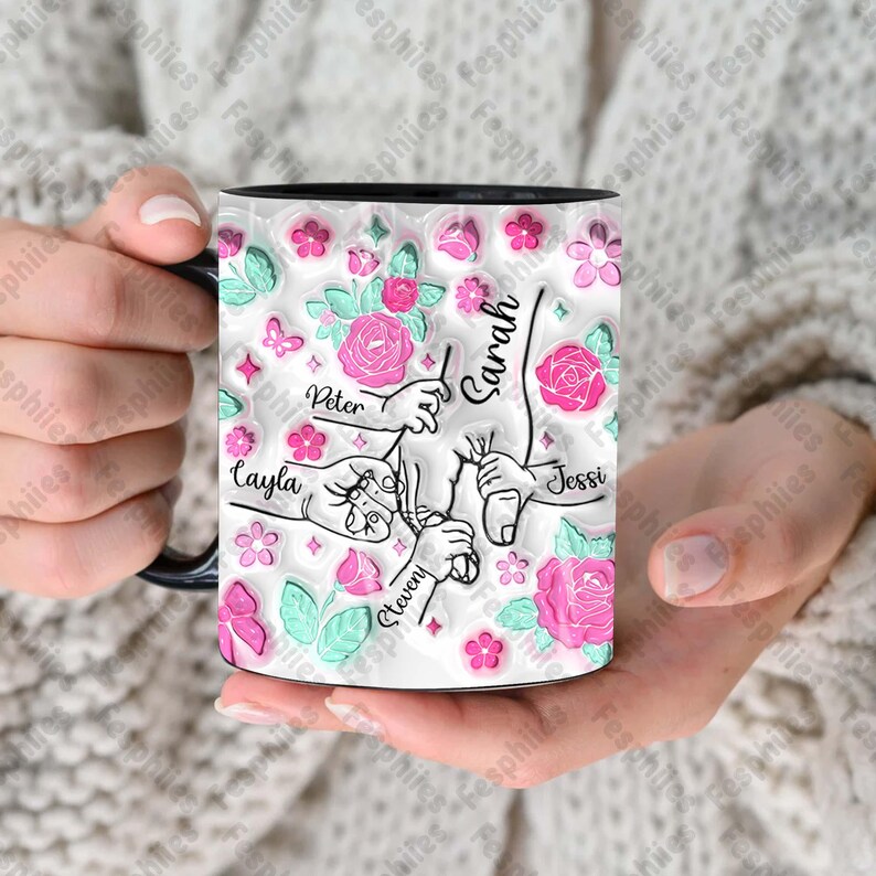 May include: White ceramic mug with a black rim and handle. The mug features a pink and green floral design with handprints and the names "Peter", "Sarah", "Layla", "Steven", and "Jessy".