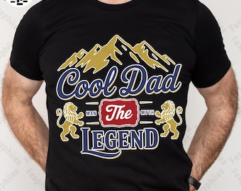 May include: A black t-shirt with a graphic design of mountains, lions, and the text "Cool Dad The Legend" in blue and gold lettering.