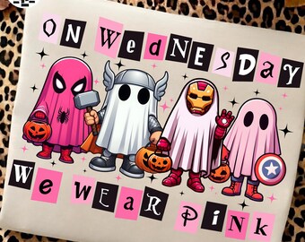 May include: A light-colored t-shirt featuring a graphic of four superheroes dressed as ghosts for Halloween, holding pumpkin buckets. The text reads ON WEDNESDAY WE WEAR PINK, with letters alternating between black and pink rectangular backgrounds.