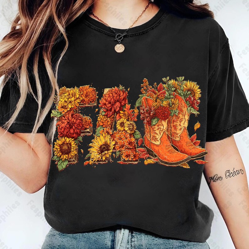 May include: Black t-shirt with a floral "FALL" design. The letters are made of sunflowers, orange and yellow chrysanthemums, and red flowers. Two orange cowboy boots are filled with flowers.