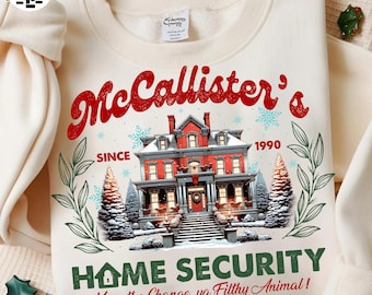 May include: Cream-colored sweatshirt with a festive design. Features the text "McCallister's" in red script above a detailed illustration of a red house with snow and Christmas trees. The phrase "Home Security" is below the house, with the text "Keep the Change, ya Filthy Animal!"