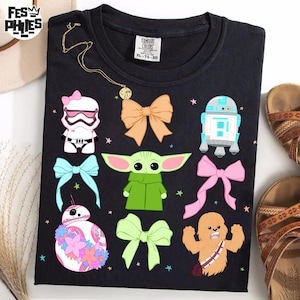May include: Black t-shirt with a graphic print of Star Wars characters, including Baby Yoda, R2-D2, and a Stormtrooper. The characters are surrounded by colorful bows.