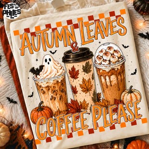 May include: A cream-colored t-shirt featuring a graphic of three coffee cups, pumpkins, and bats. The text reads AUTUMN LEAVES & COFFEE PLEASE. One cup has a ghost, one has maple leaves, and one has marshmallows. The design includes an orange checkered border.