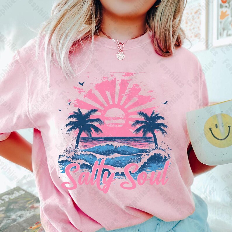 May include: Pink t-shirt featuring a graphic of a sunset over the ocean with palm trees and the text "Salty Soul".