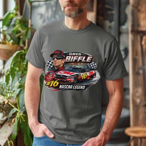 May include: A grey t-shirt with a graphic of Greg Biffle, a race car, and the text "#16 NASCAR LEGEND." The design includes a portrait of Biffle wearing sunglasses and a racing cap, along with a red and black race car.