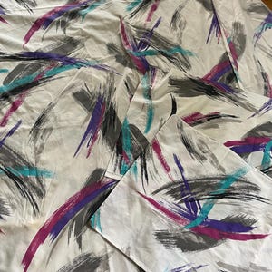 May include: A white fabric set featuring a repeating abstract pattern of bold, sweeping brushstrokes in shades of charcoal gray, vibrant magenta, and bright teal. The design consists of layered, textured marks across the textile surface.