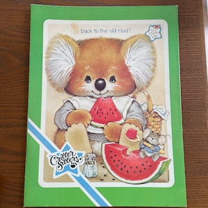 May include: A vintage children's book cover featuring a cartoon koala bear holding a watermelon slice. The cover has a green border and includes the text "back to the old rind!" and "Critter Sitters". A small mouse is also present.