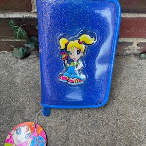 Puede incluir: Estuche azul brillante con un dise&ntilde;o de ni&ntilde;a de dibujos animados. El estuche tiene cierre de cremallera y ribete azul a juego. Una etiqueta de Lisa Frank est&aacute; adjunta.