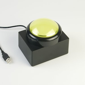 May include: A black USB button with a yellow button on top. The button is connected to a computer via a USB cable.