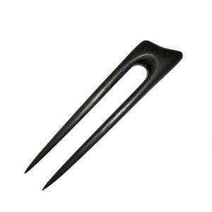 May include: A dark gray wooden hair fork with a curved top and two long, pointed prongs. The hair accessory is designed for securing hair in an updo style. The hair fork is set against a white background.