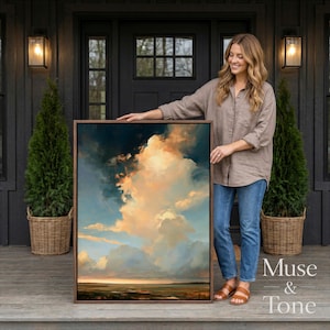May include: A rectangular framed wall art piece featuring a dramatic oil painting of a sunset sky with large, voluminous clouds in shades of gold, orange, and deep blue, hovering over a dark, flat horizon line at the bottom of the composition.