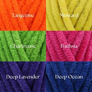 May include: Five spools of yarn in different colors: tangerine, mustard, chartreuse, fuchsia, and deep lavender. The yarn is a soft, fuzzy texture.