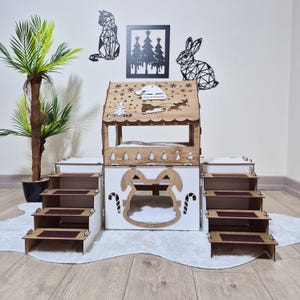 May include: A wooden pet house with a house-shaped roof and a bunny-shaped entrance. The roof has a Christmas theme with snowflakes, a Christmas tree, and the name "Brownie". The house has steps on each side and is set on a white rug.