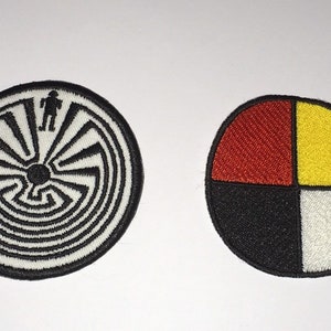 May include: Two embroidered patches. The first patch is white with a black and white spiral maze design. The second patch is a circle divided into four sections: red, yellow, black, and white.