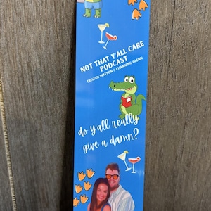 May include: Blue bookmark featuring cartoon alligators, cocktail illustrations, and the text "NOT THAT Y'ALL CARE PODCAST" and "do y'all really give a damn?". Includes a photo of a couple.