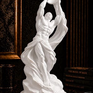 Puede incluir: Escultura blanca de una figura musculosa sosteniendo una corona en alto. La figura está envuelta en tela fluida y se alza sobre una base rocosa. Es una pieza decorativa.