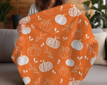 Puede incluir: Manta de tiro naranja con un patrón de calabaza blanca. La manta presenta un patrón repetitivo de calabazas con diferentes diseños, incluyendo algunas con detalles intrincados.