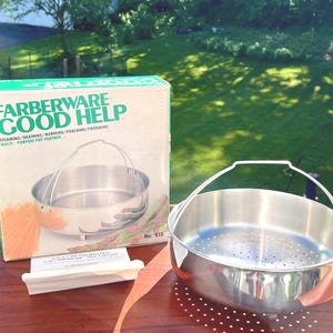 May include: A Farberware Good Help multi-purpose pot partner, with a stainless steel steamer basket and a box with the product name and features. The box is green and white, and the basket has a handle.