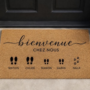 Peut inclure: Un paillasson rectangulaire en fibre de coco beige avec le texte noir "bienvenue CHEZ NOUS" en haut. Sous le texte se trouvent cinq paires d'empreintes de pas et de pattes noires, étiquetées avec les noms MATHIS, CHLOÉ, MANON, GABIN et NALA.