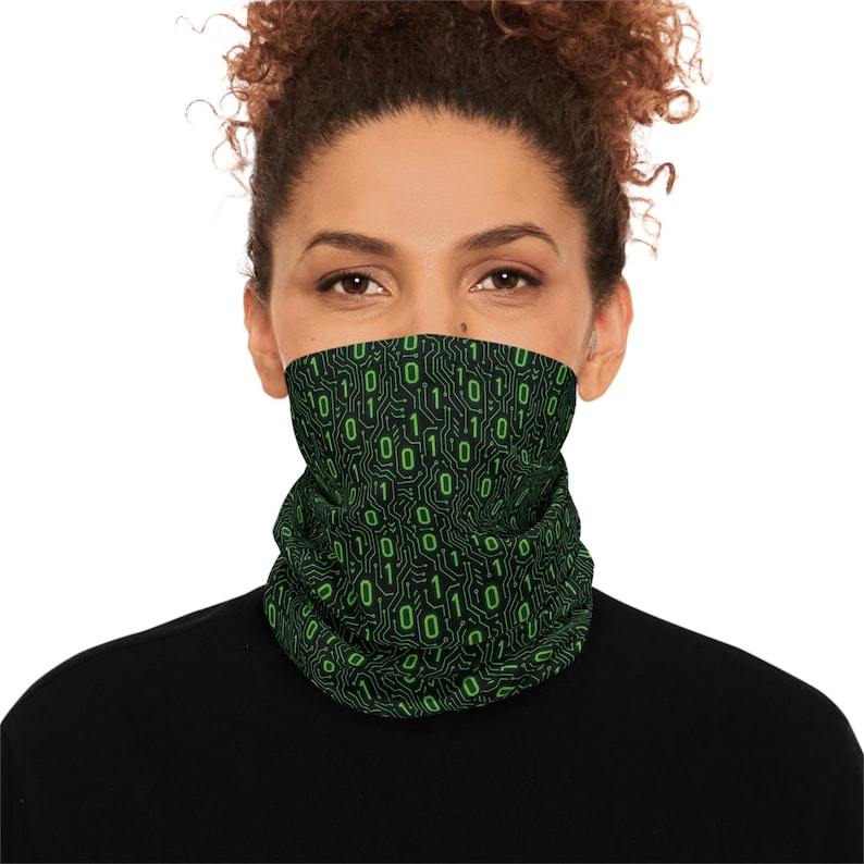May include: A black neck gaiter with a repeating pattern of green binary code. The digital design features the numbers 0 and 1, resembling a circuit board. The gaiter is worn around the neck and covers the lower face.